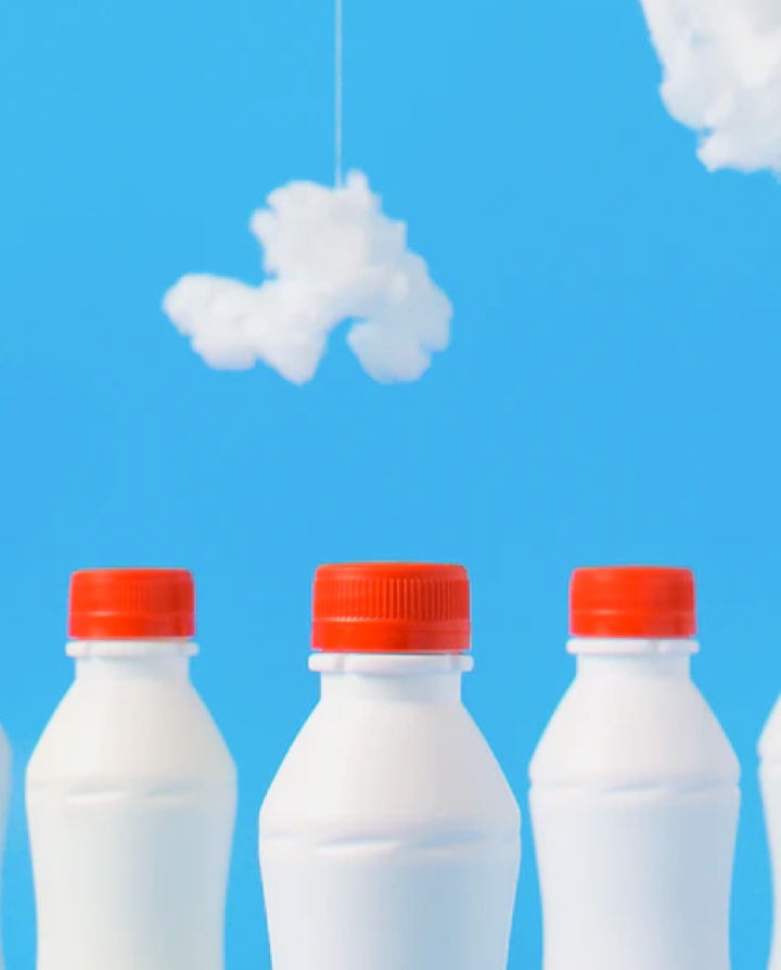 Image of Milk bottles with red caps and a blue background with clouds.