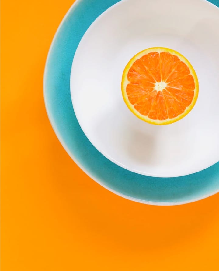 Image of an orange on a white plate with a blue edge.